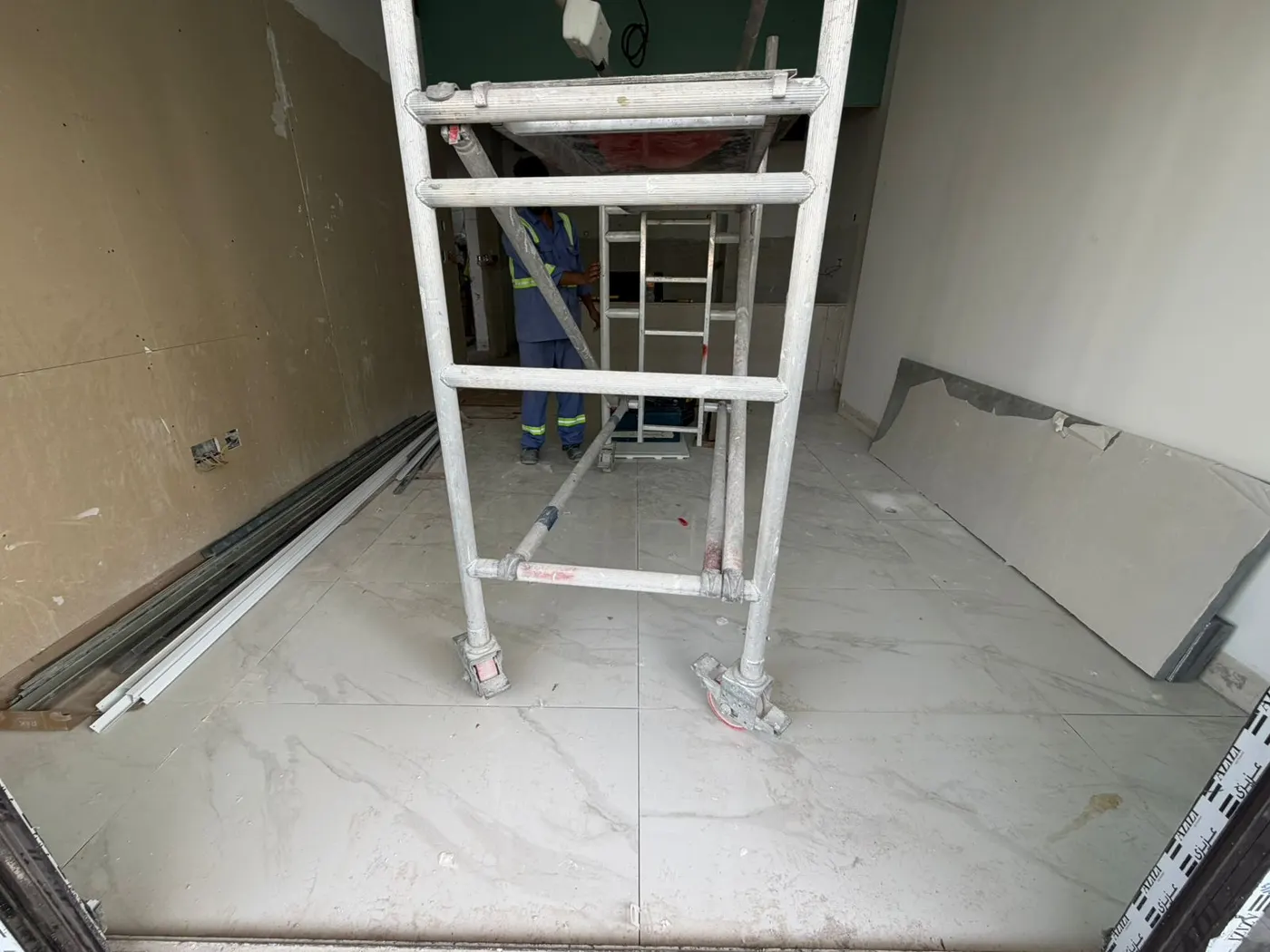 Mobile access tower set up in a tiled room for high-level ceiling works