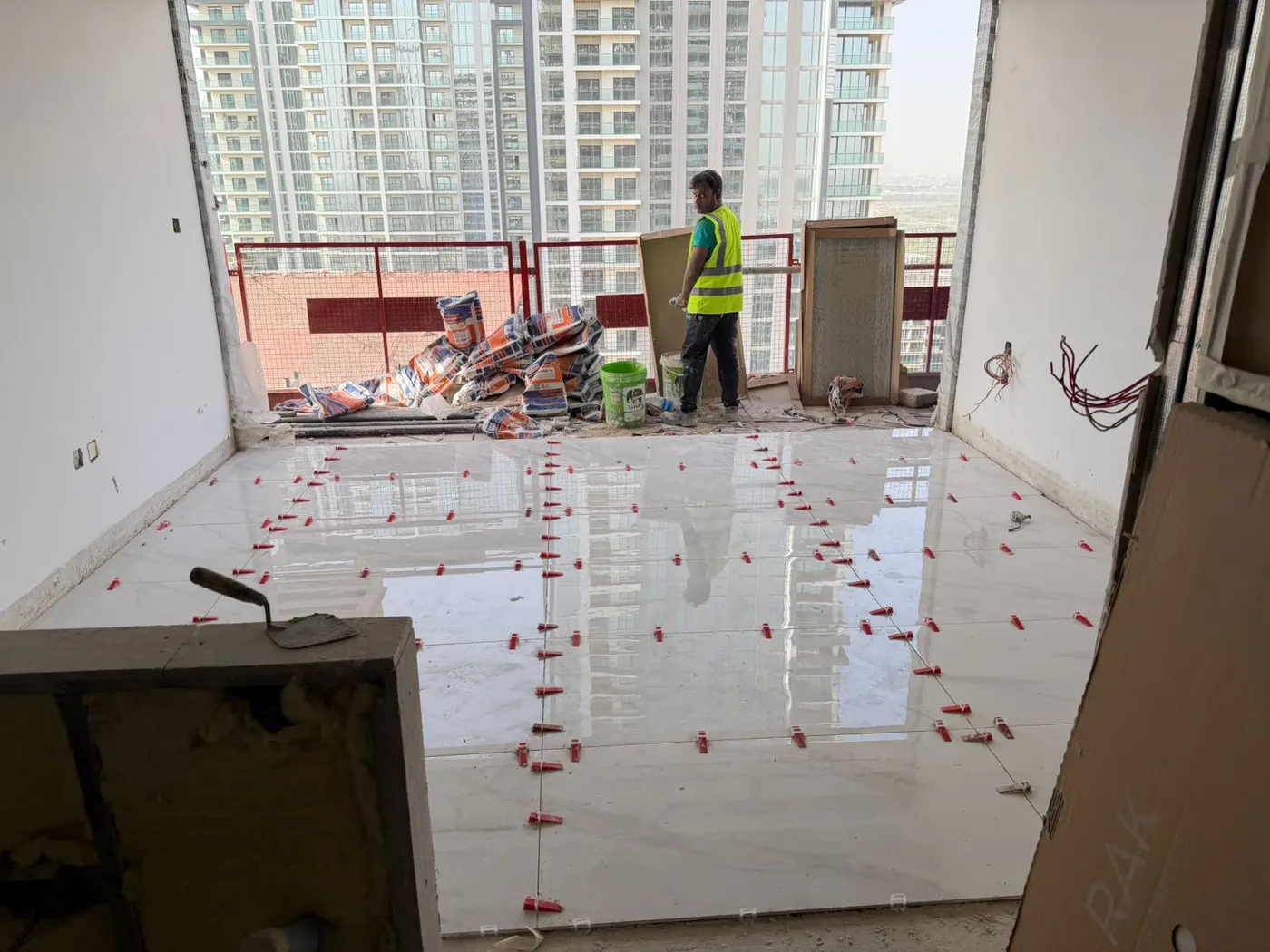 Floor tiles held flat by levelling clips while the adhesive cures