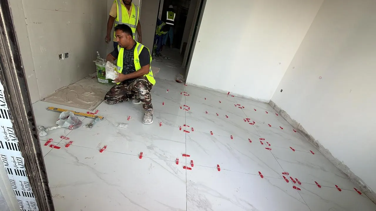 Technician bedding a large-format floor tile and setting levelling clips