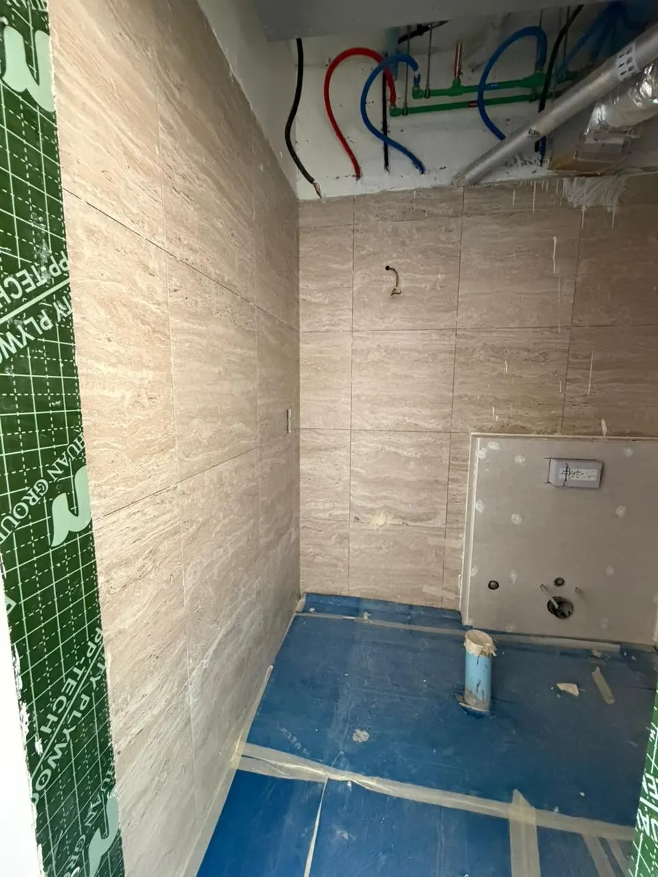 Wet area showing first-fix pipework and conduit at high level with tiled walls